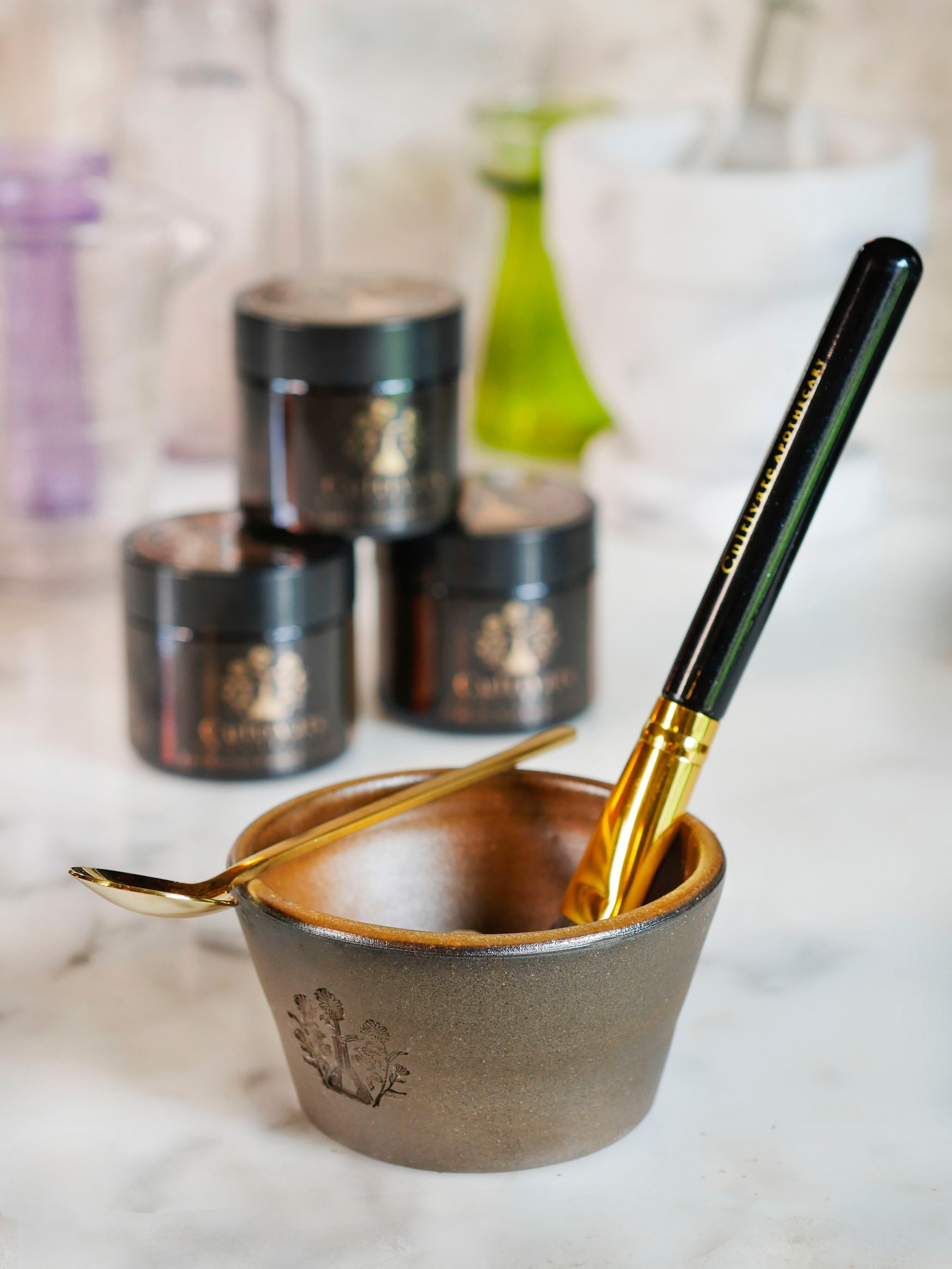 Face mask bowl set including a face mask bowl, face mask brush, and gold face mask mixing spoon.